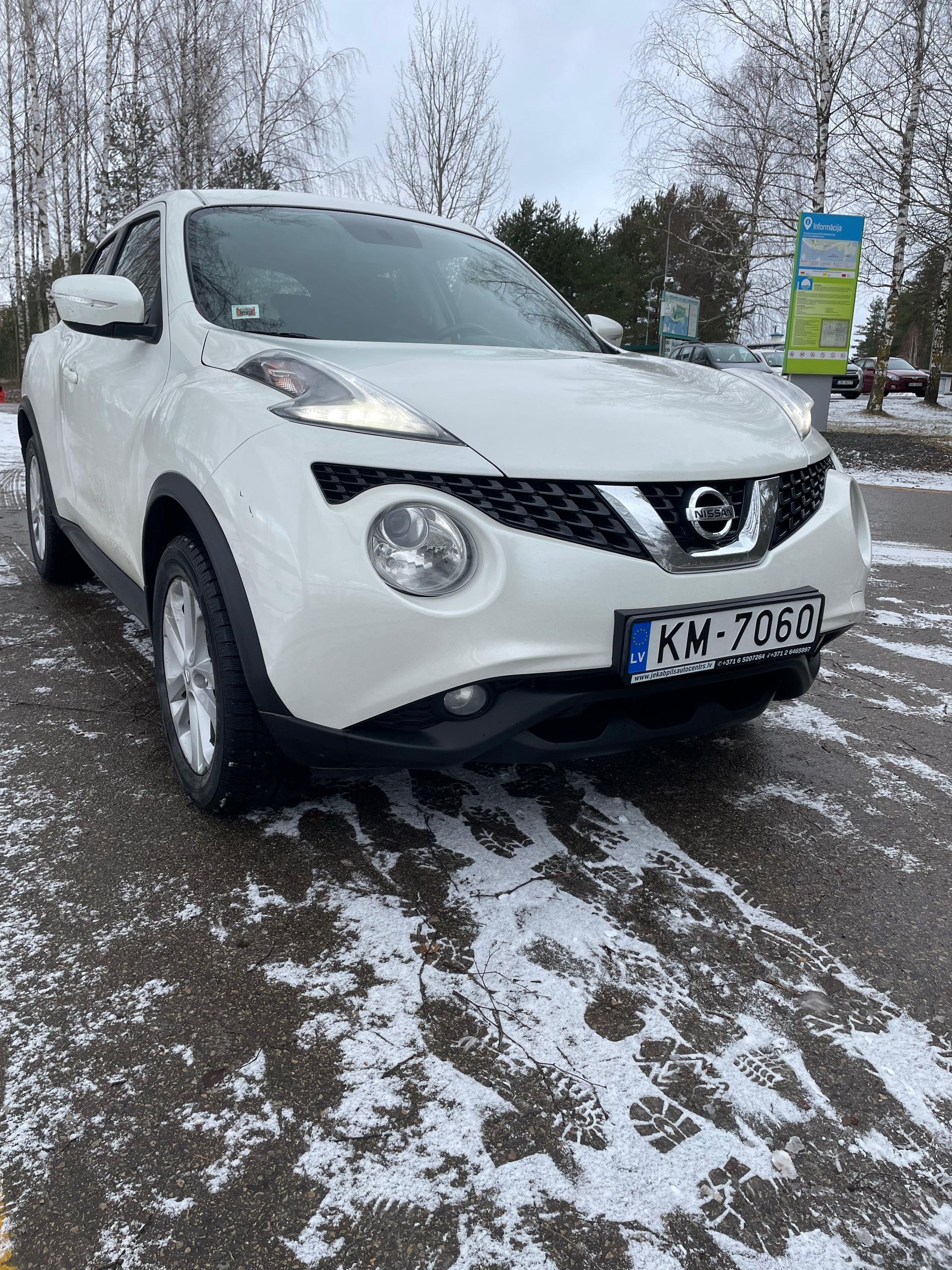 Sniegā stāvvietā stāv balts nissan juke.