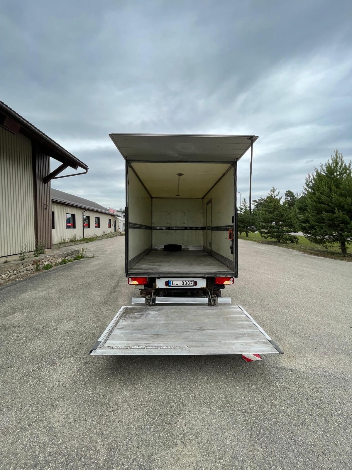 Kravas automašīna ar atvērtām aizmugurējām durvīm ir novietota stāvvietā.