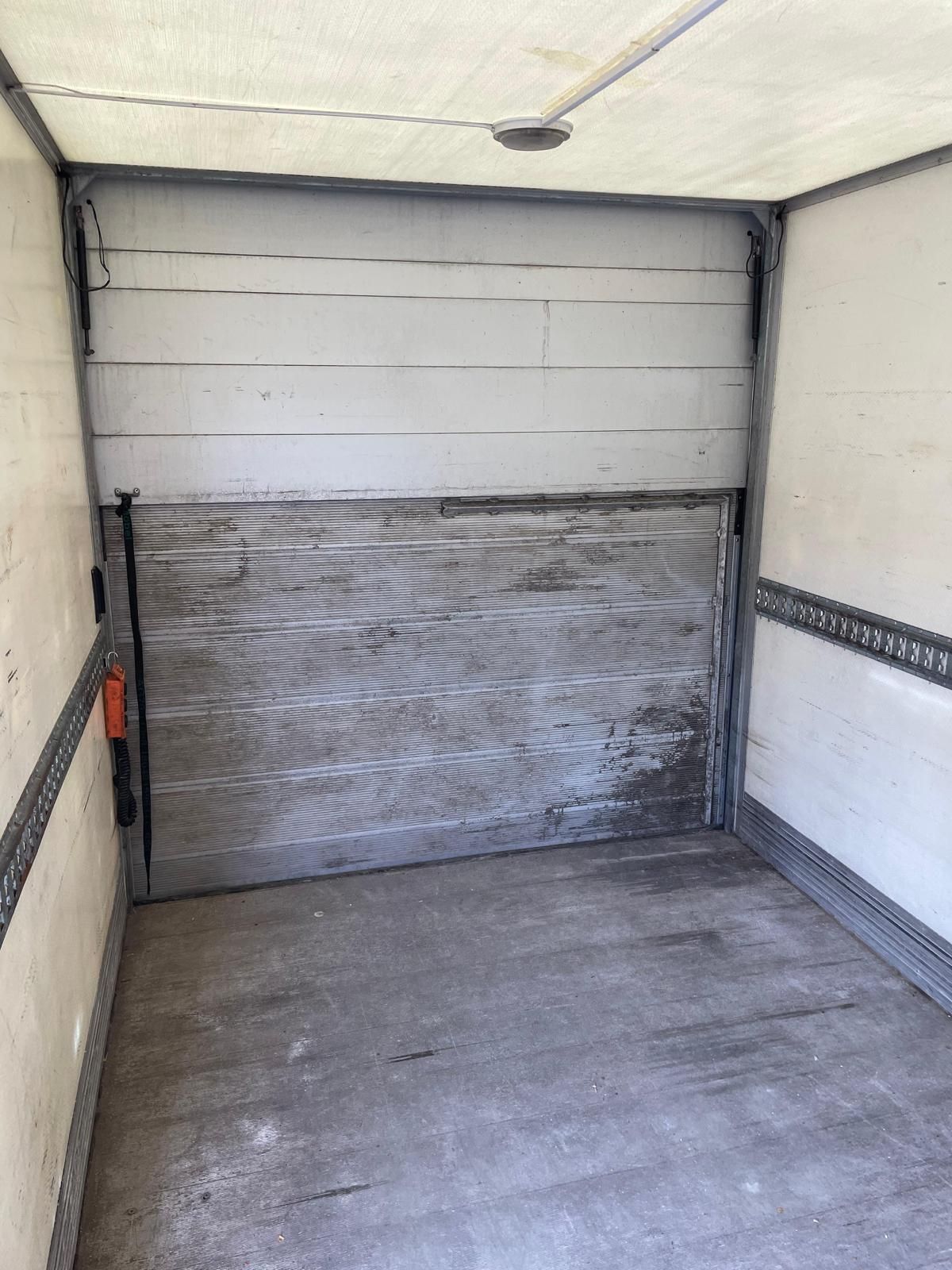 Tukša garāža ar atvērtām garāžas durvīm un betona grīdu.