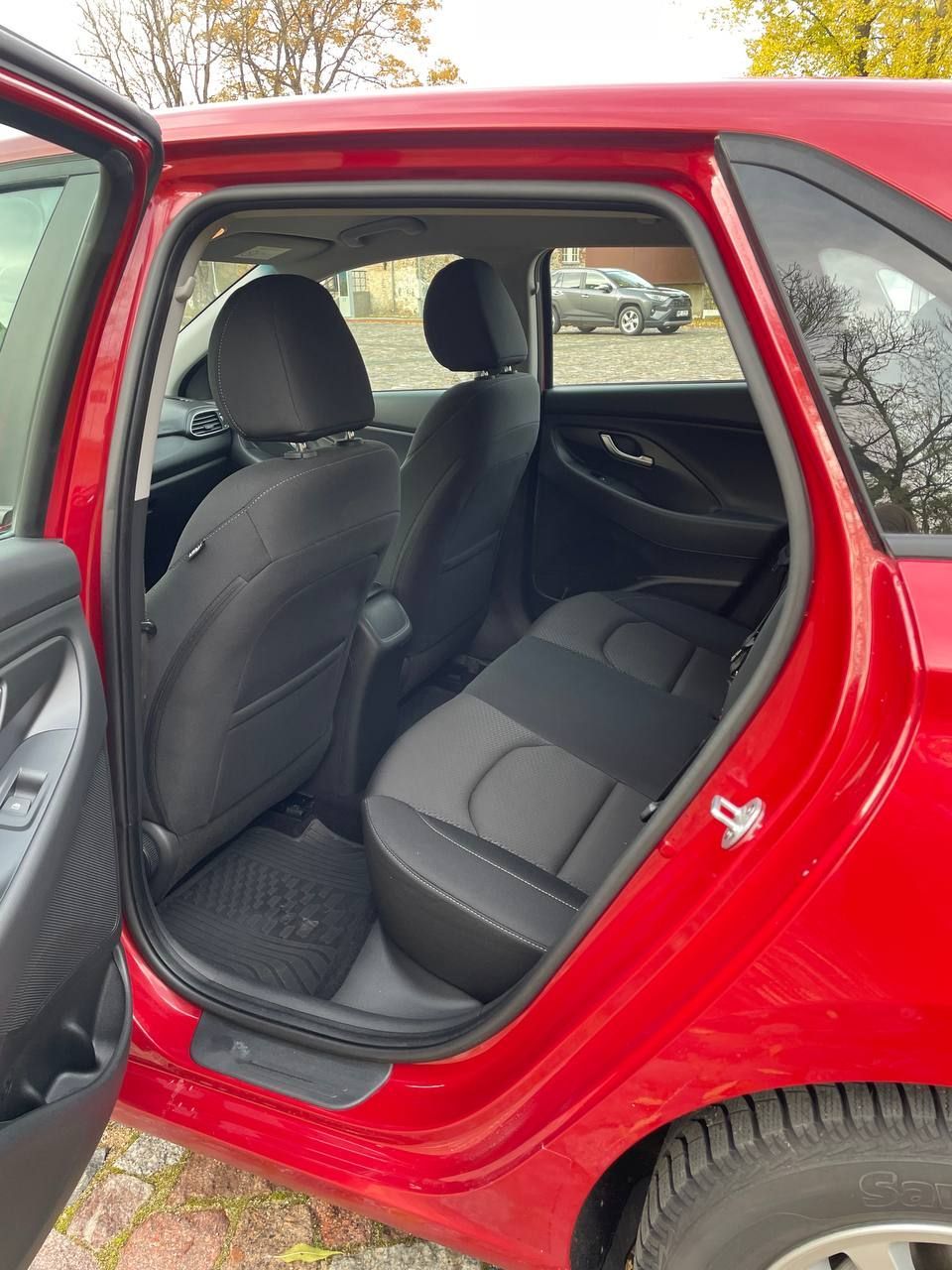 Sarkanas automašīnas aizmugurējais sēdeklis ar atvērtām durvīm.