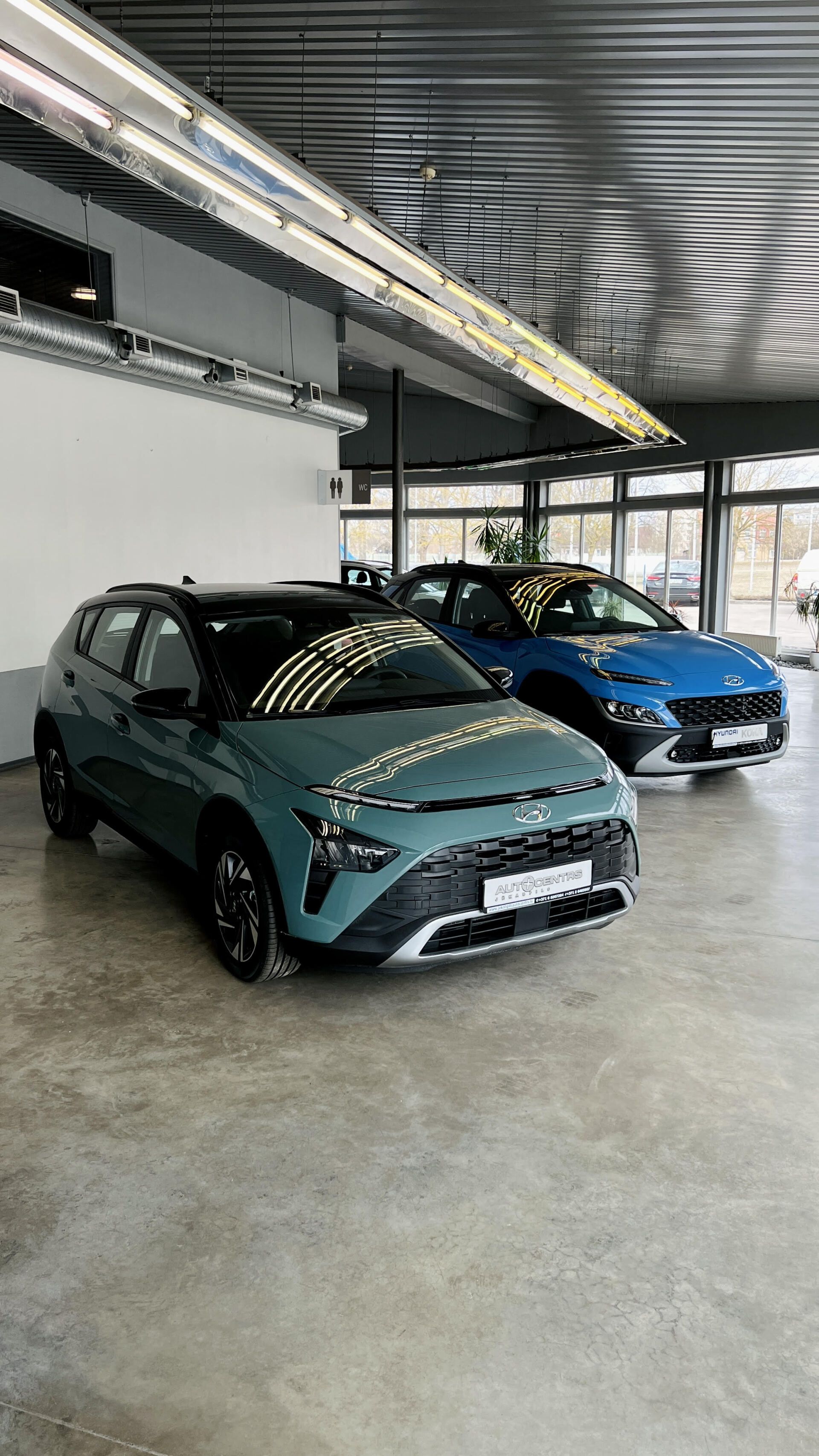 Divas automašīnas ir novietotas blakus viena otrai salonā.