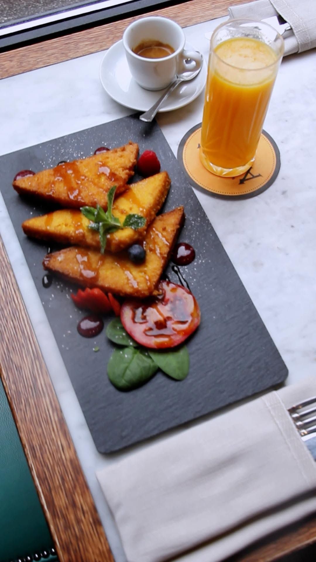 French toast con frutta e sciroppo su una tavola di ardesia, più succo d'arancia ed espresso.