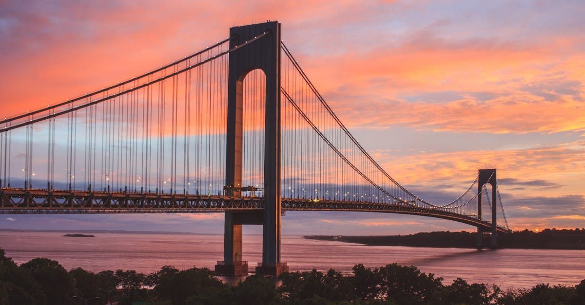 A suspension bridge over a body of water at sunset.