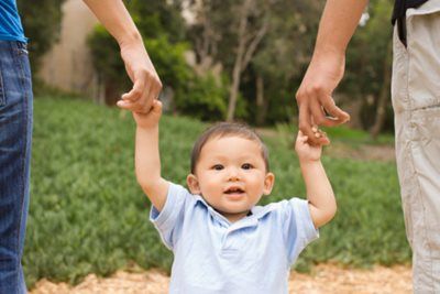 Toddler walking with his parents