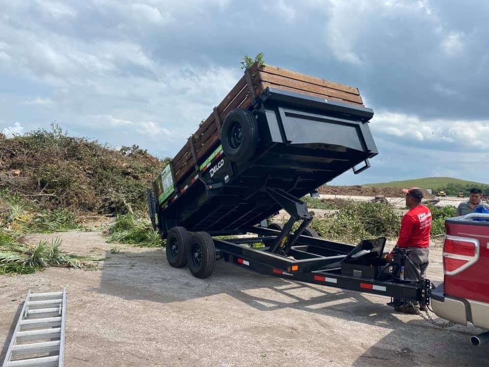 A man in a red shirt is standing next to a dump trailer.