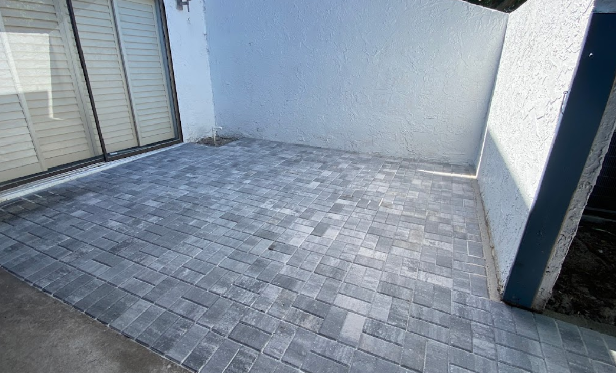 A patio with a sliding glass door and a brick floor.
