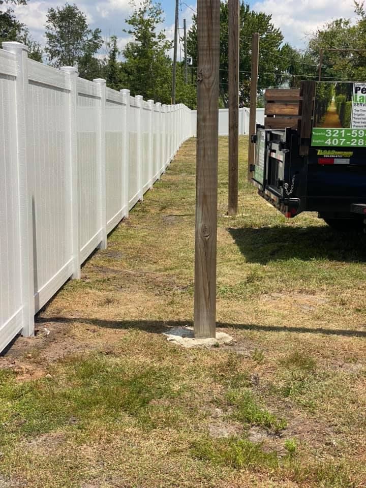 A white pick up truck is parked next to a white fence.