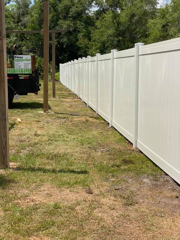 A white fence is sitting in the middle of a grassy field.