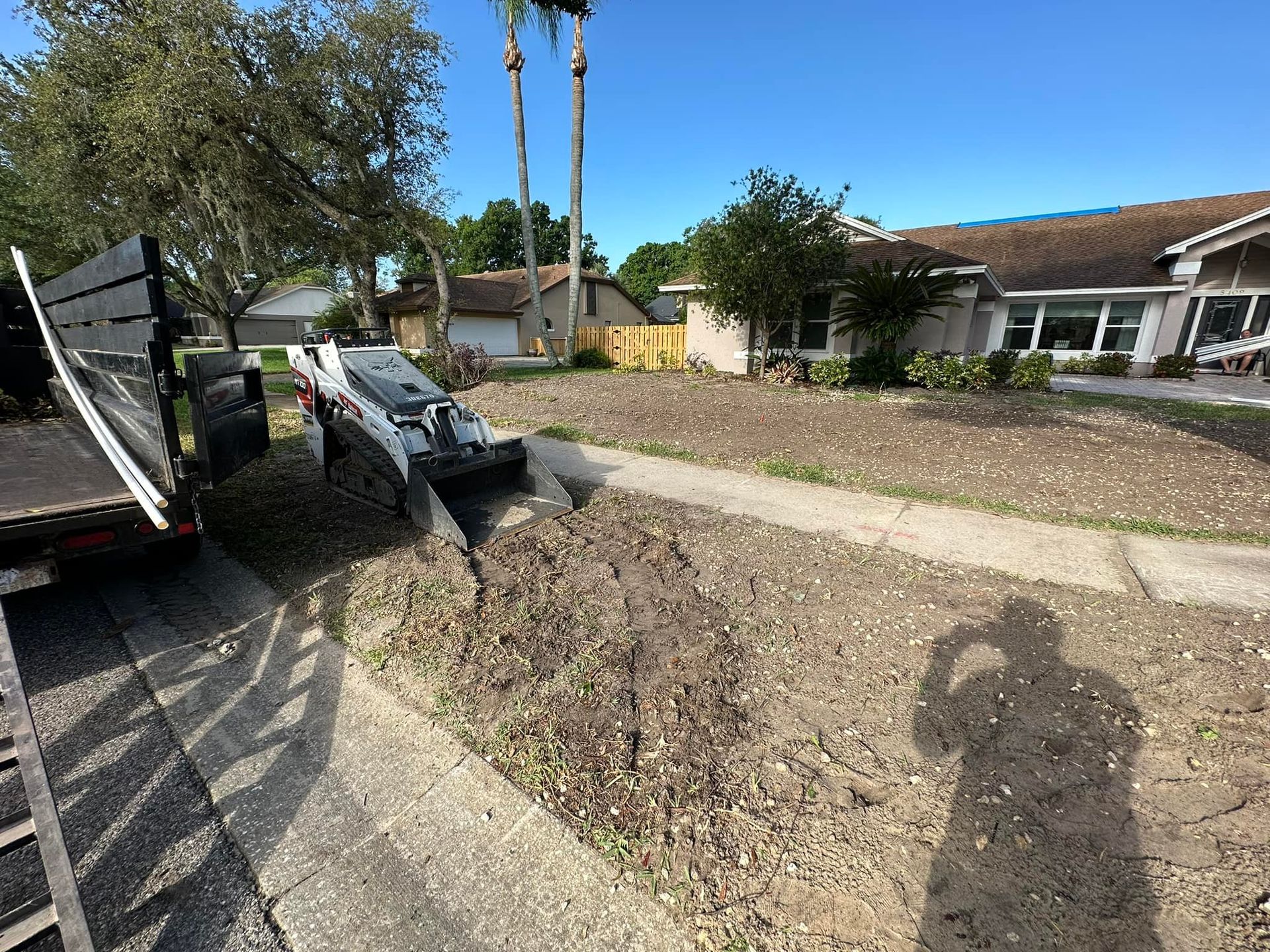 A shadow of a person is cast on the sidewalk in front of a house.