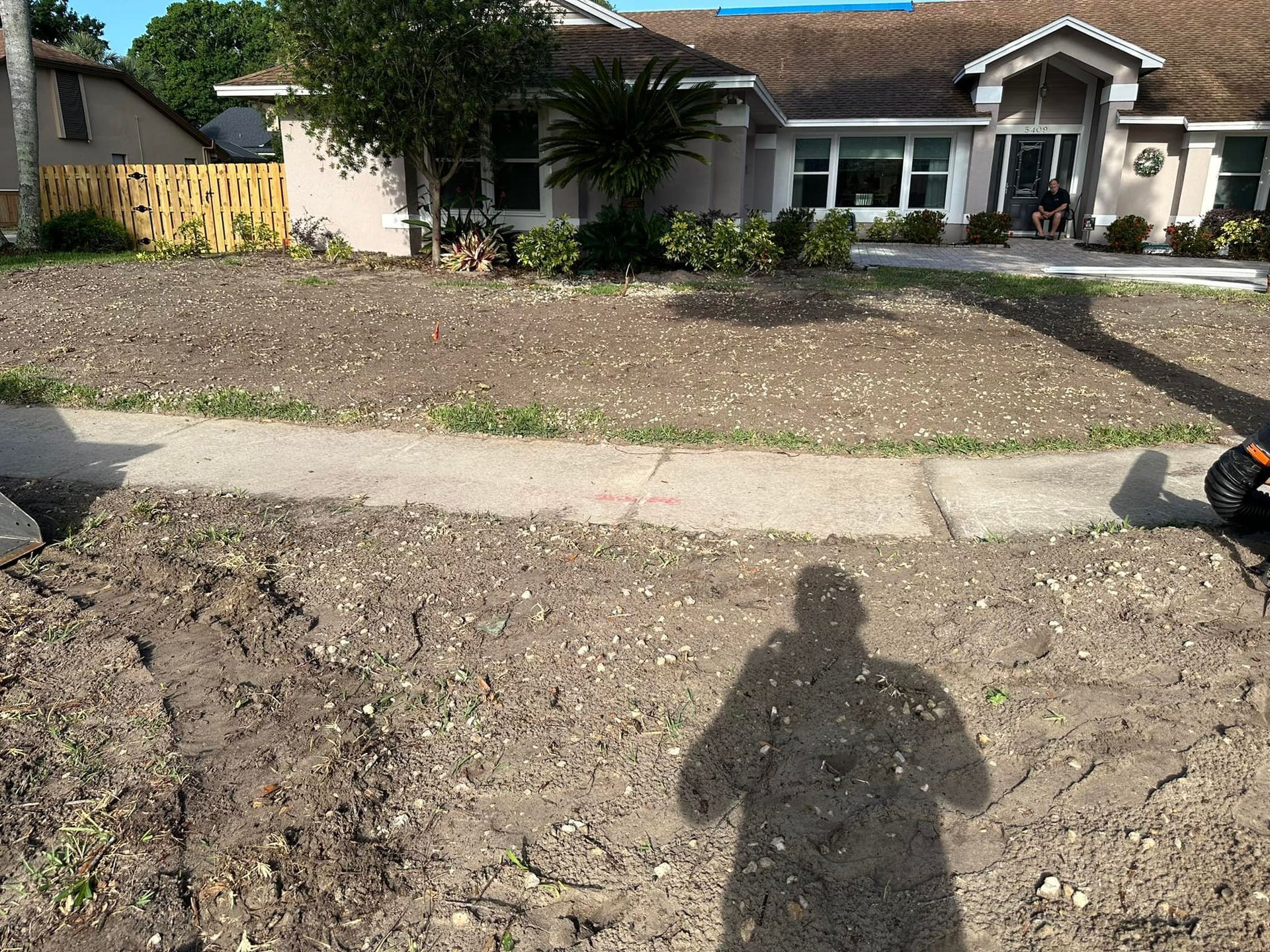 A shadow of a person is cast on the ground in front of a house