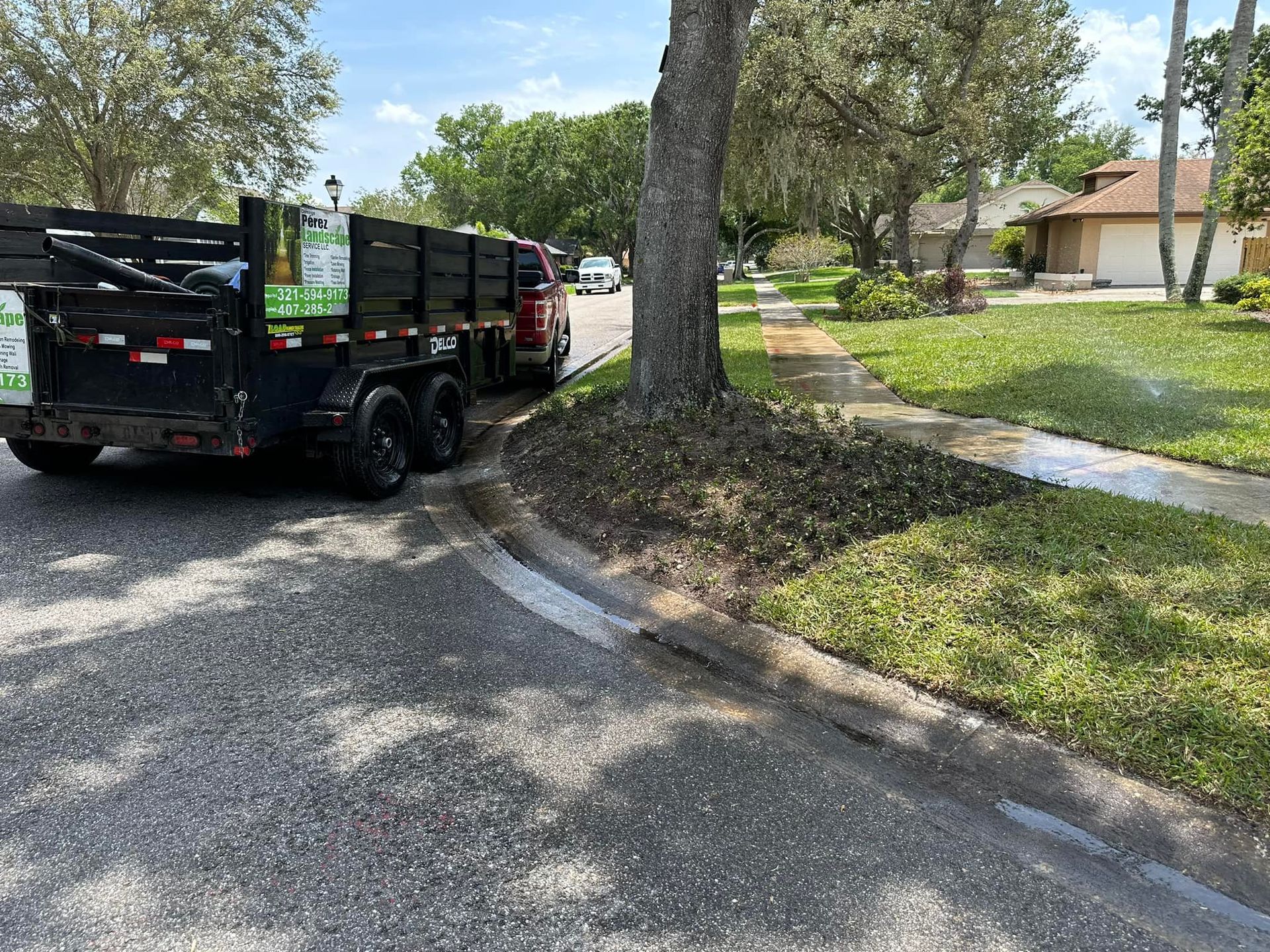A dump truck is parked on the side of the road next to a tree.