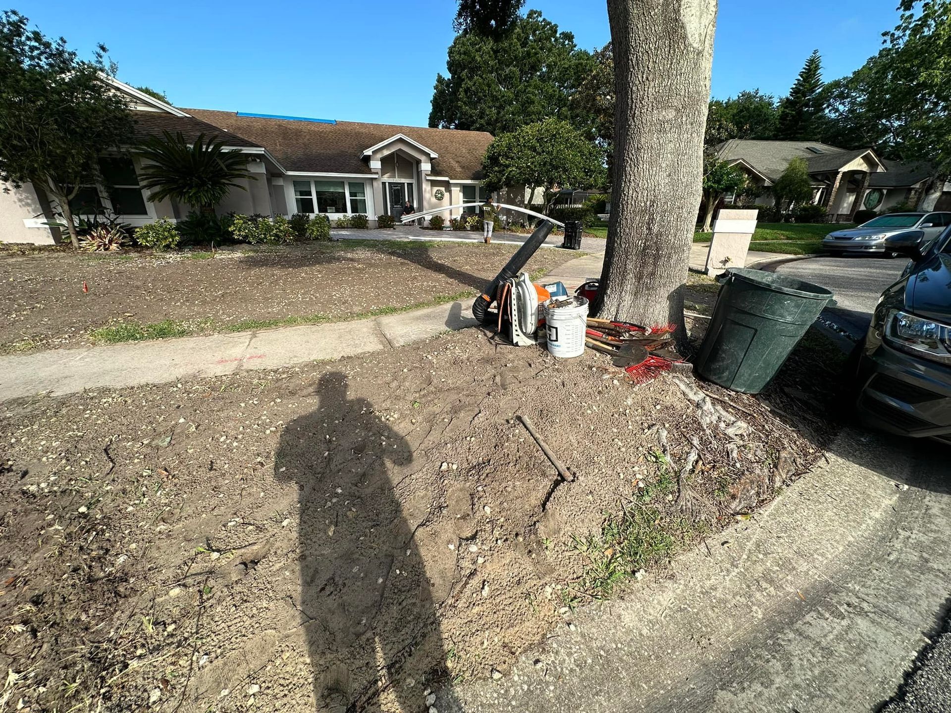 A shadow of a person is cast on the ground in front of a house