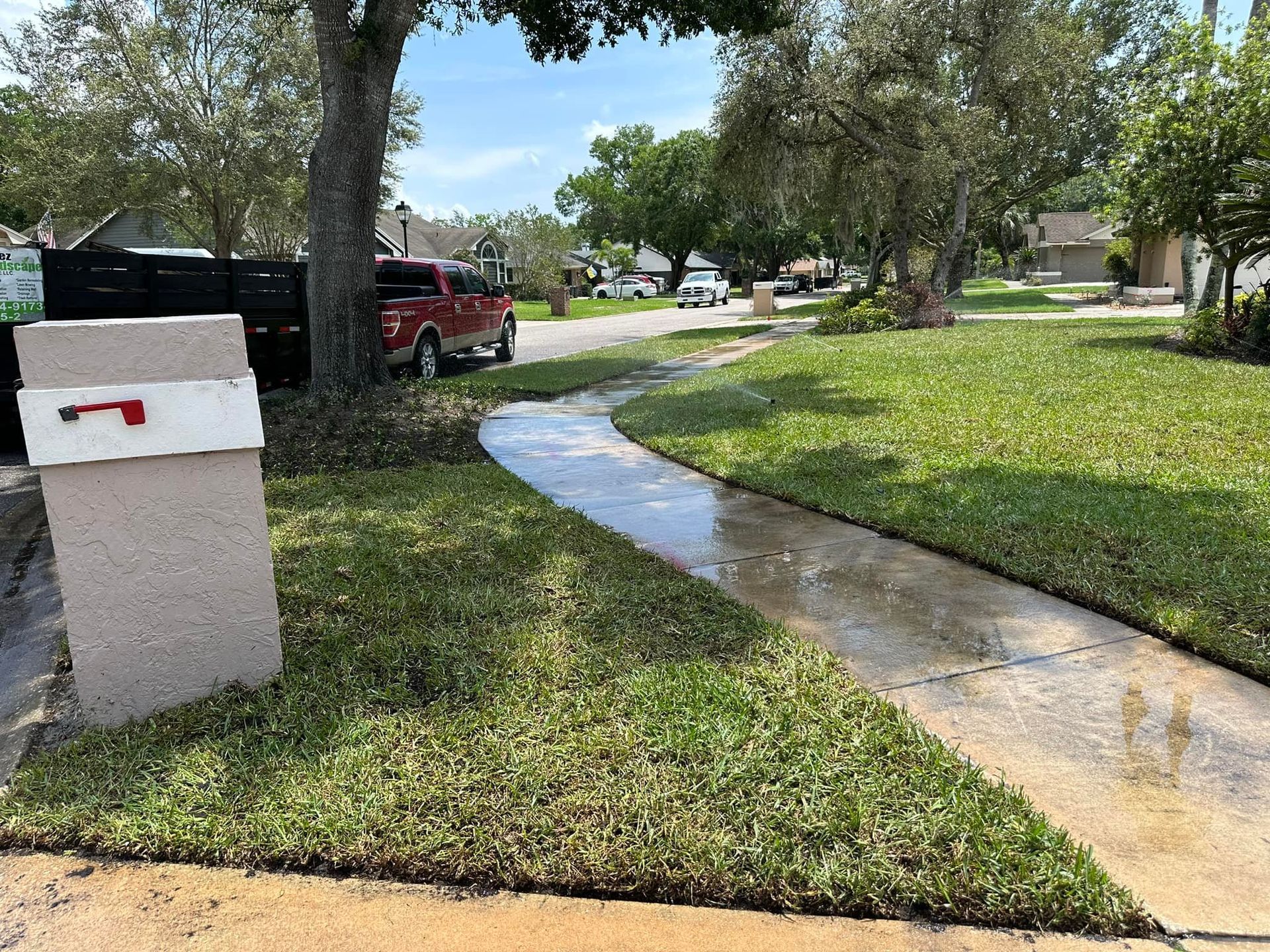 A red truck is parked on the side of the road next to a mailbox.