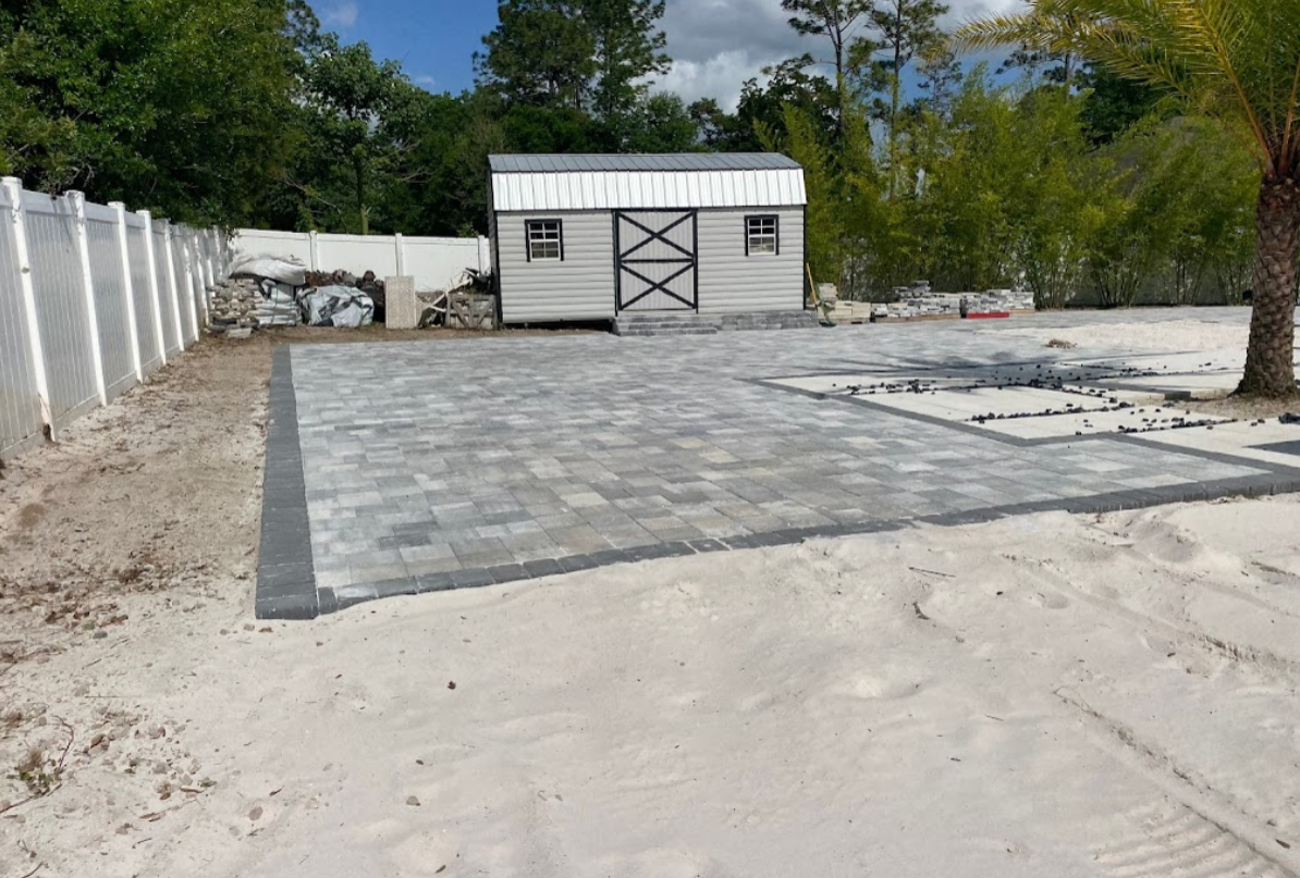 A shed is sitting in the middle of a brick driveway.