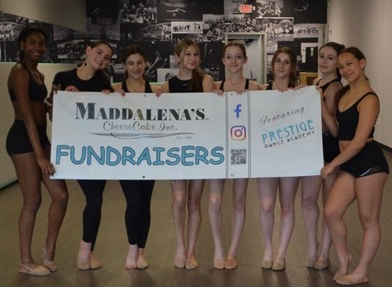 Two women are standing next to a wooden sign that says fundraisers.