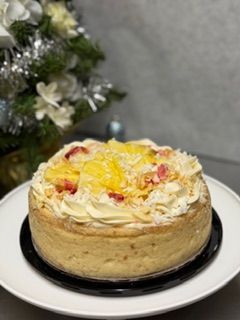 Toasted Coconut Pineapple CheeseCake topped with Fresh Pineapple, more coconut and dried strawberries with a cream cheese icing border