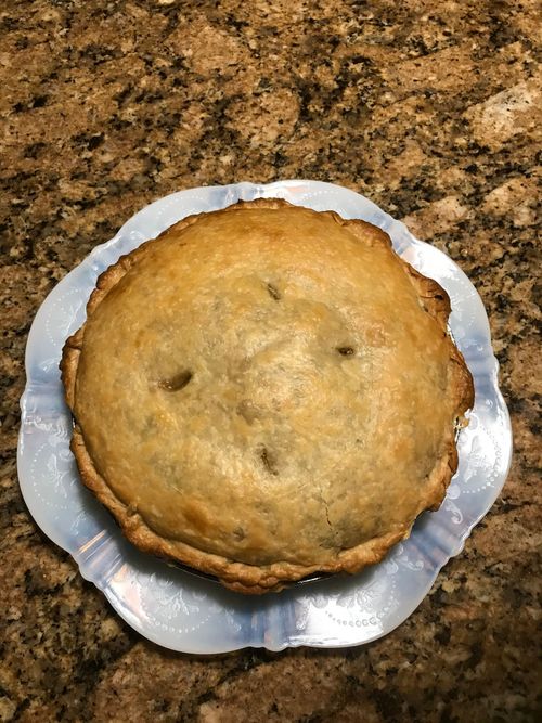 A pie is sitting on a blue plate on a counter.