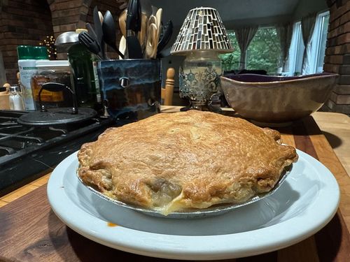 A pie is sitting on a blue plate on a counter.
