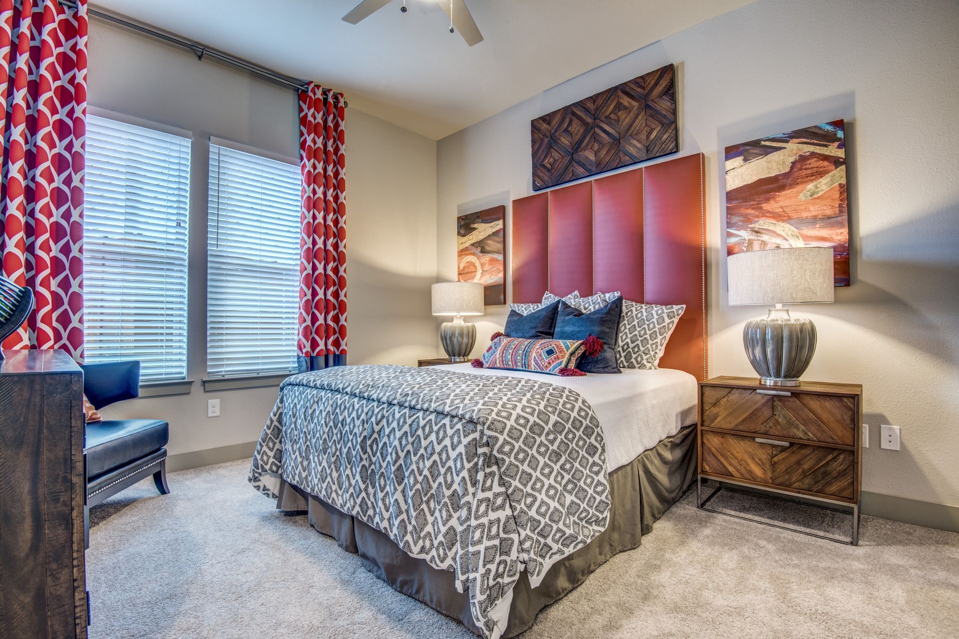 A bedroom with a large bed, two nightstands, a chair,and a ceiling fan at Two99 Monroe offers apartments for rent in Roanoke, TX.