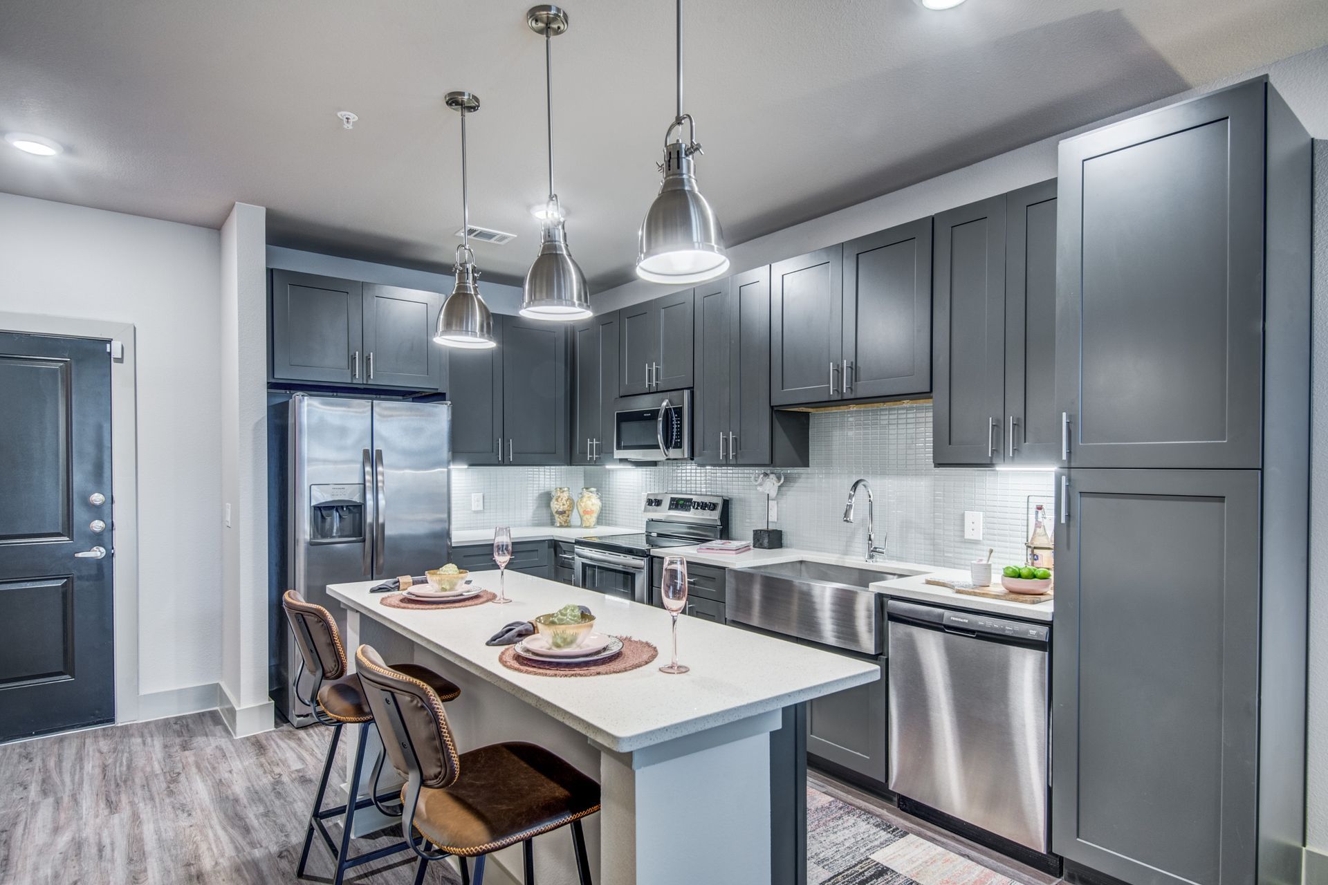 Side view of the apartment kitchen with gray cabinets, stainless steel appliances, and a large island at Two99 Monroe offers apartments for rent in Roanoke, TX.