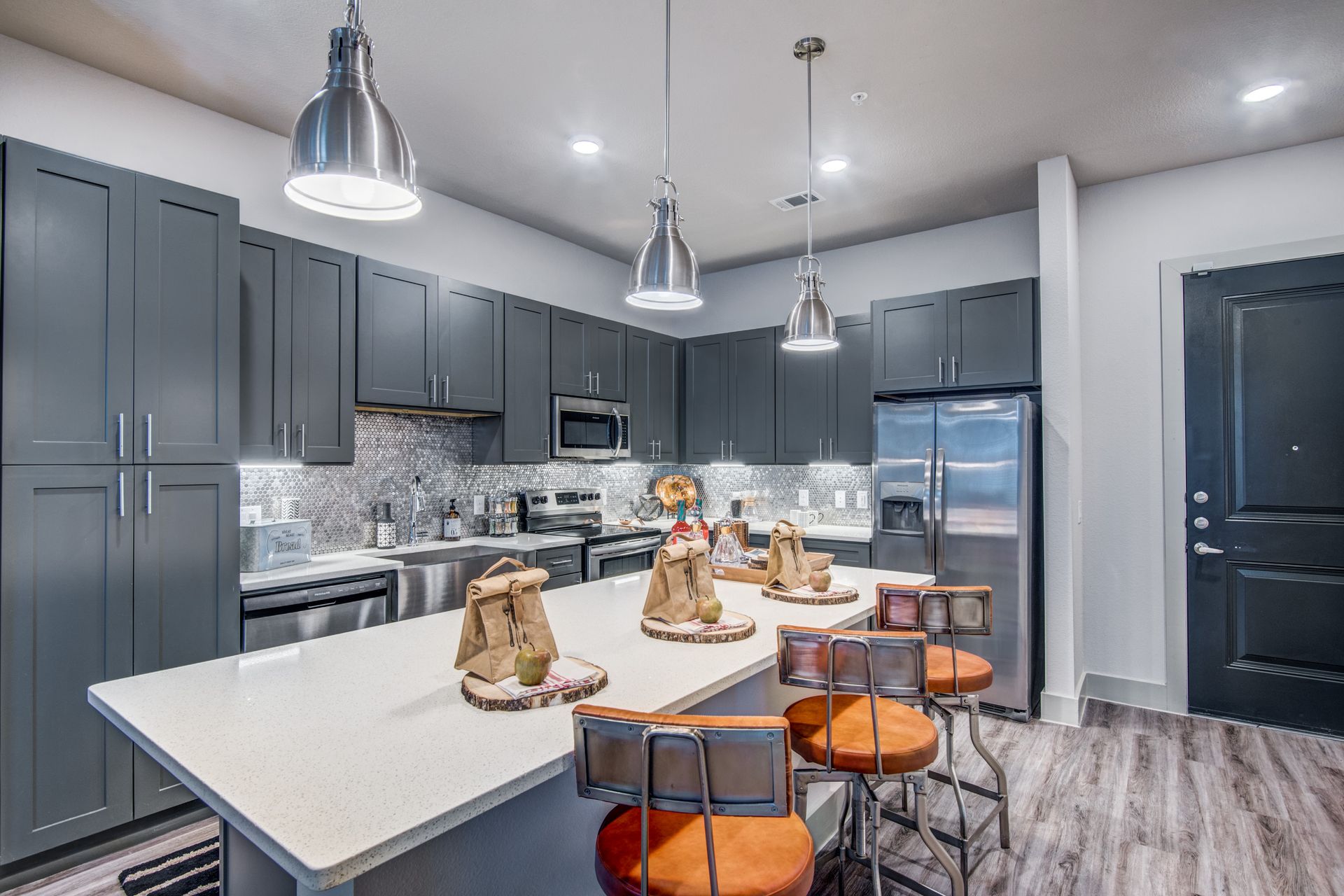 A kitchen with gray cabinets, stainless steel appliances, and a large island at Two99 Monroe offers apartments for rent in Roanoke, TX, near Downtown.