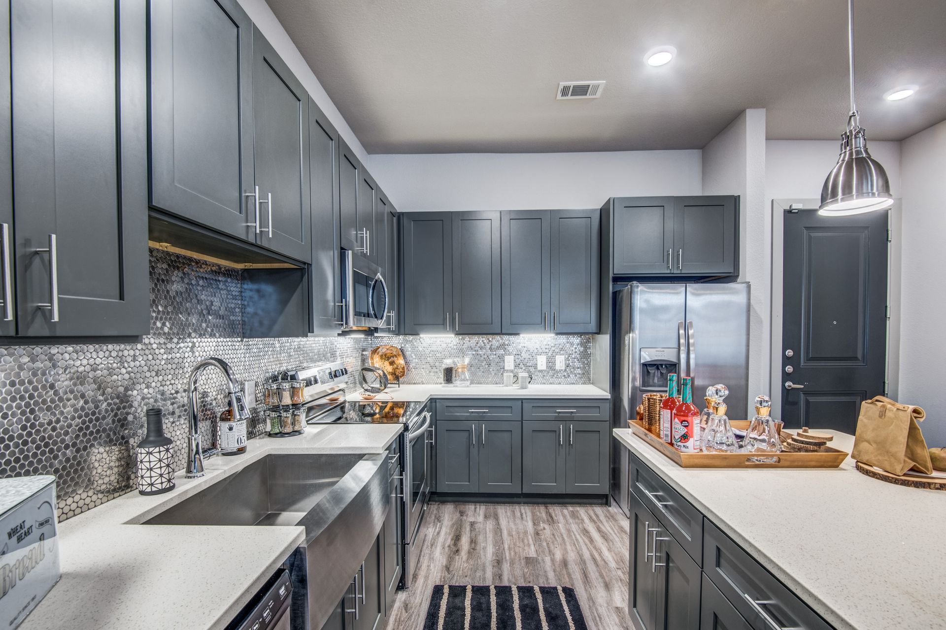 A kitchen with gray cabinets, stainless steel appliances, a sink, and a refrigerator at Two99 Monroe offers apartments for rent in Roanoke, TX.