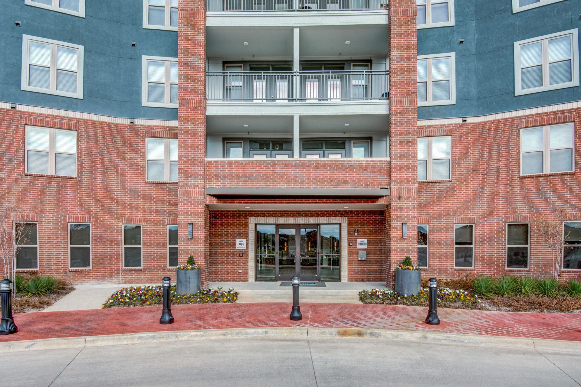 A large brick apartment building with numerous windows and balconies at Two99 Monroe offers apartments for rent in Roanoke, TX.