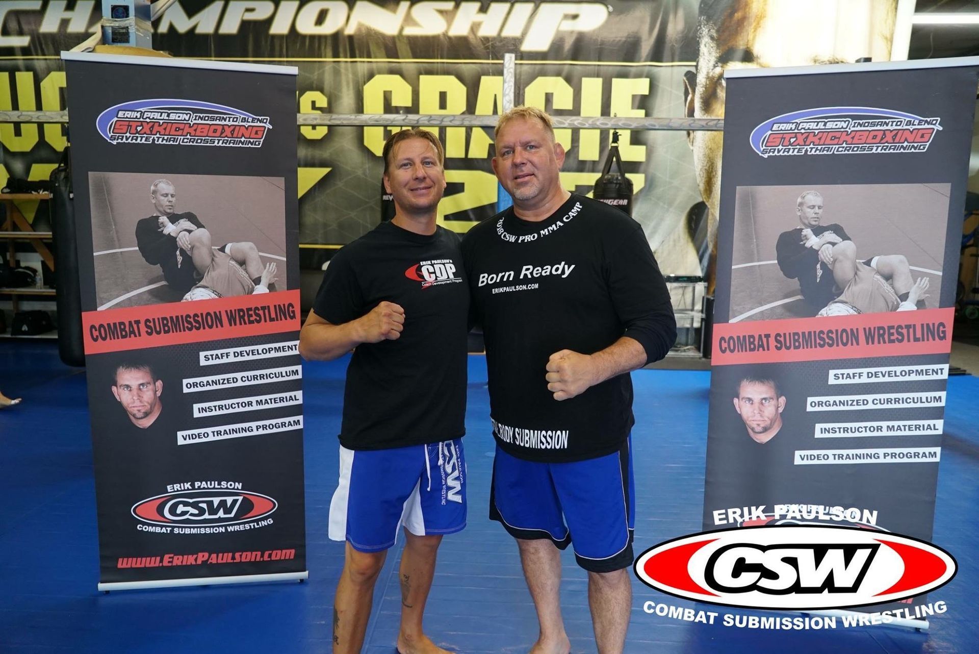 Two men standing next to each other in front of csw banners