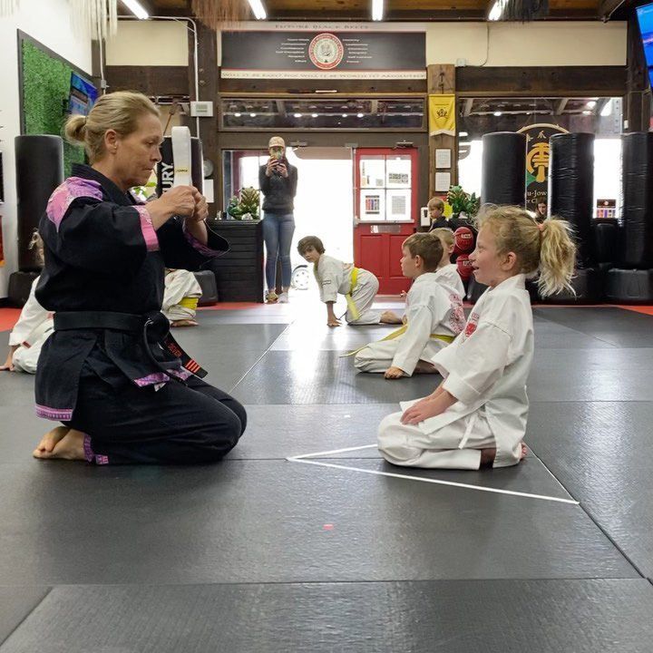 A woman is kneeling down in front of a group of children