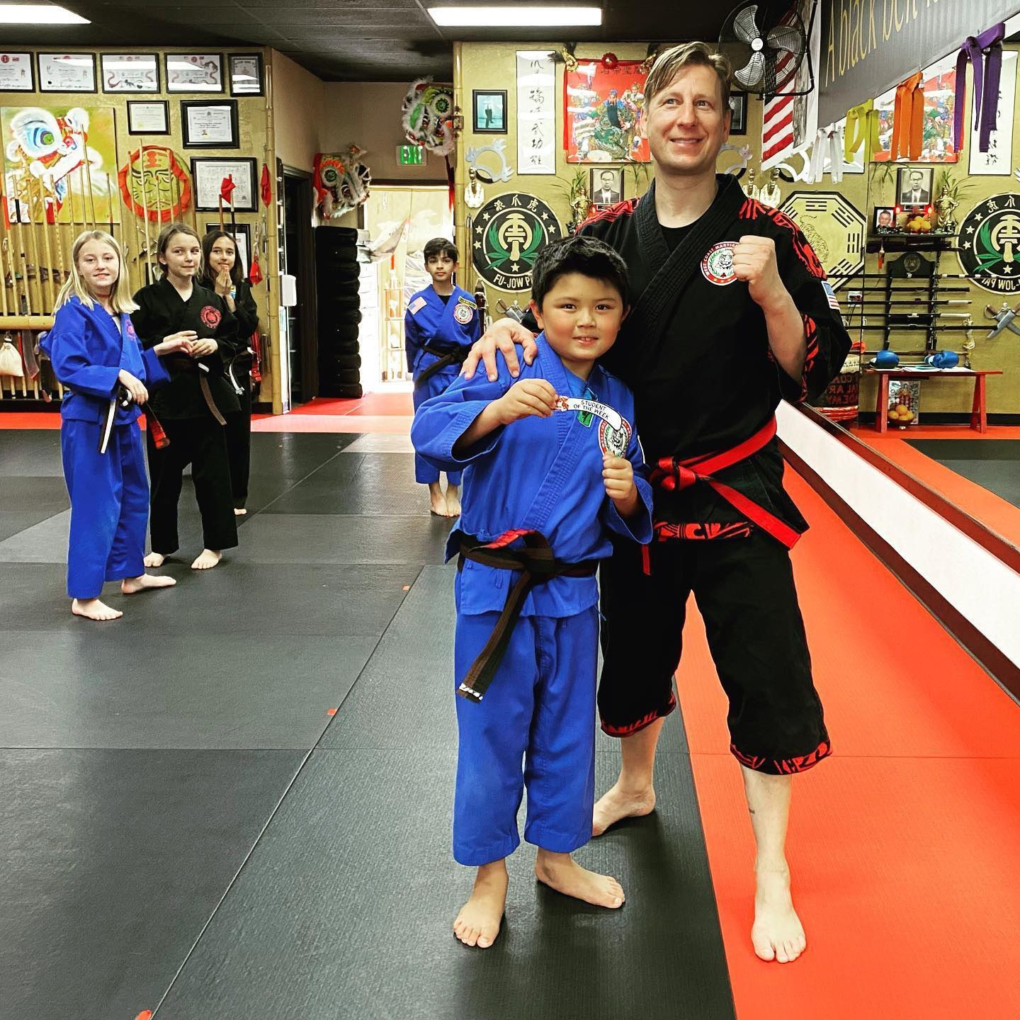 A man and a boy are posing for a picture in a martial arts gym