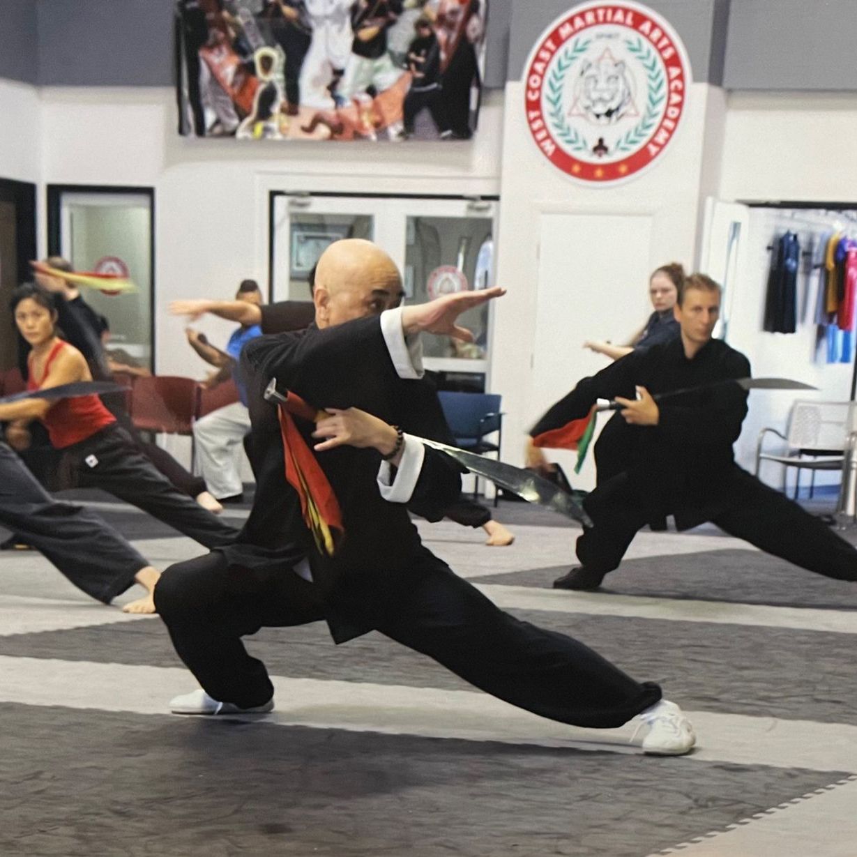 A group of people are practicing martial arts in front of a sign that says martial arts academy