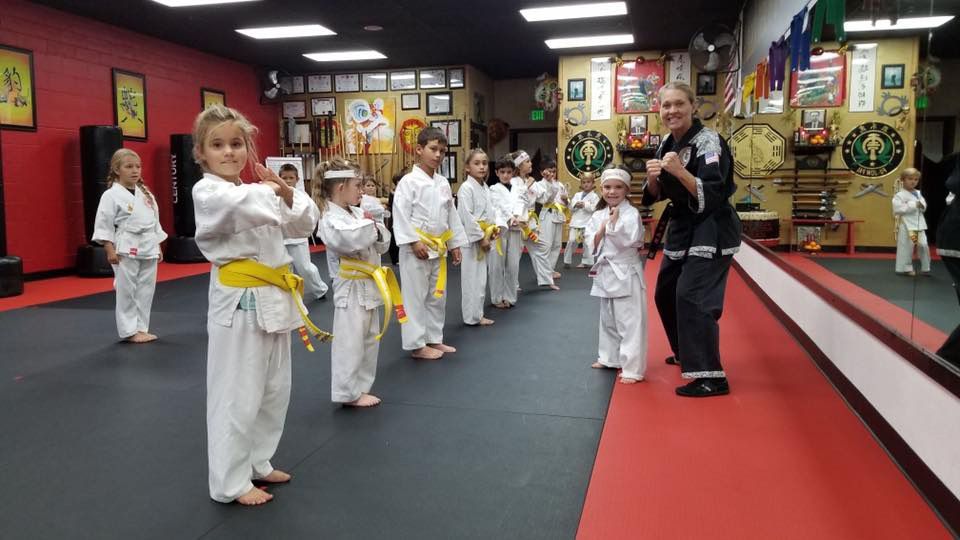 A group of children are practicing martial arts in a gym.