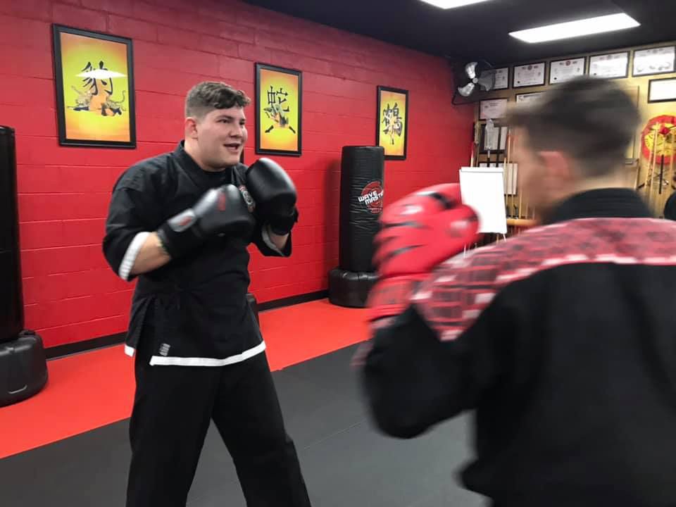 Two men are boxing in a gym with red walls.