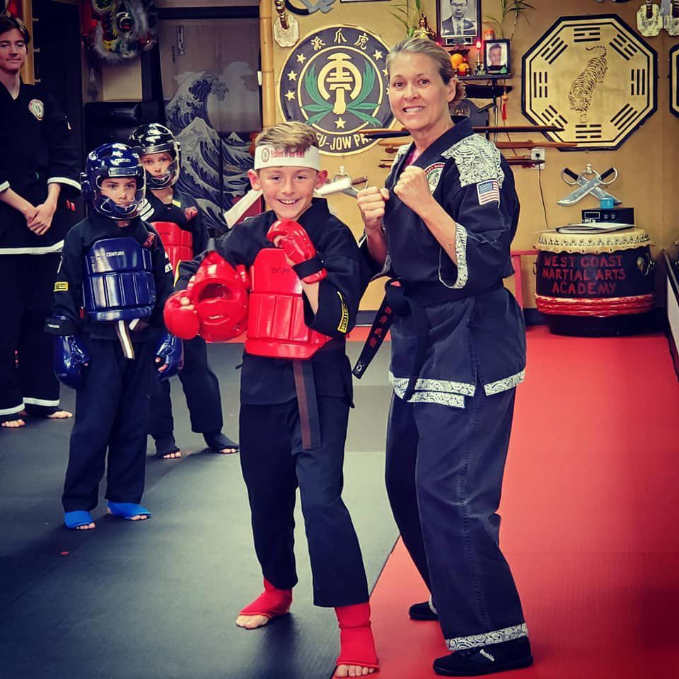 A woman stands next to a boy in a martial arts academy