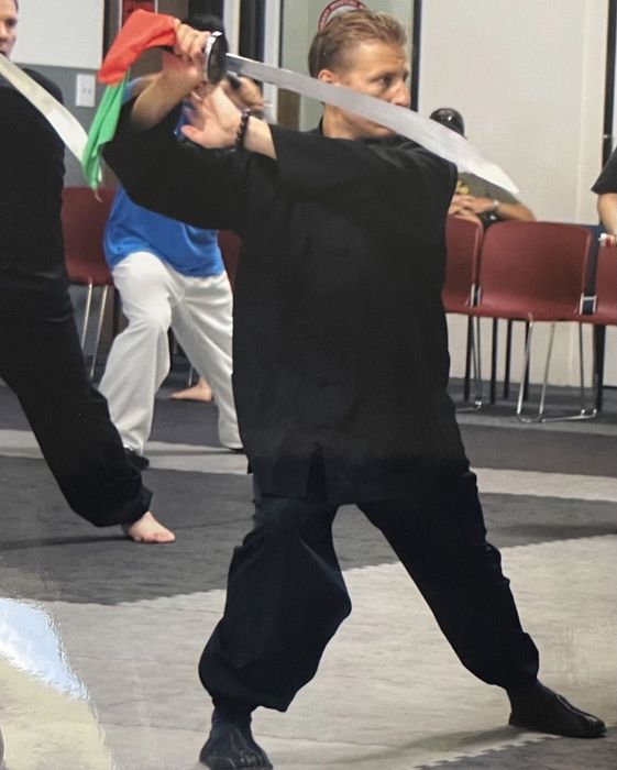 A man and a little girl are posing for a picture in front of a sign that says fv jujitsu