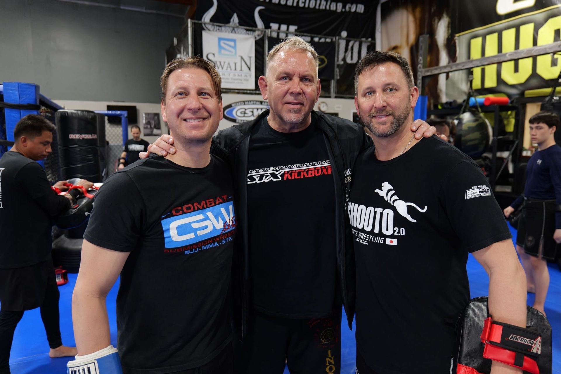 Three men are posing for a picture in a gym.