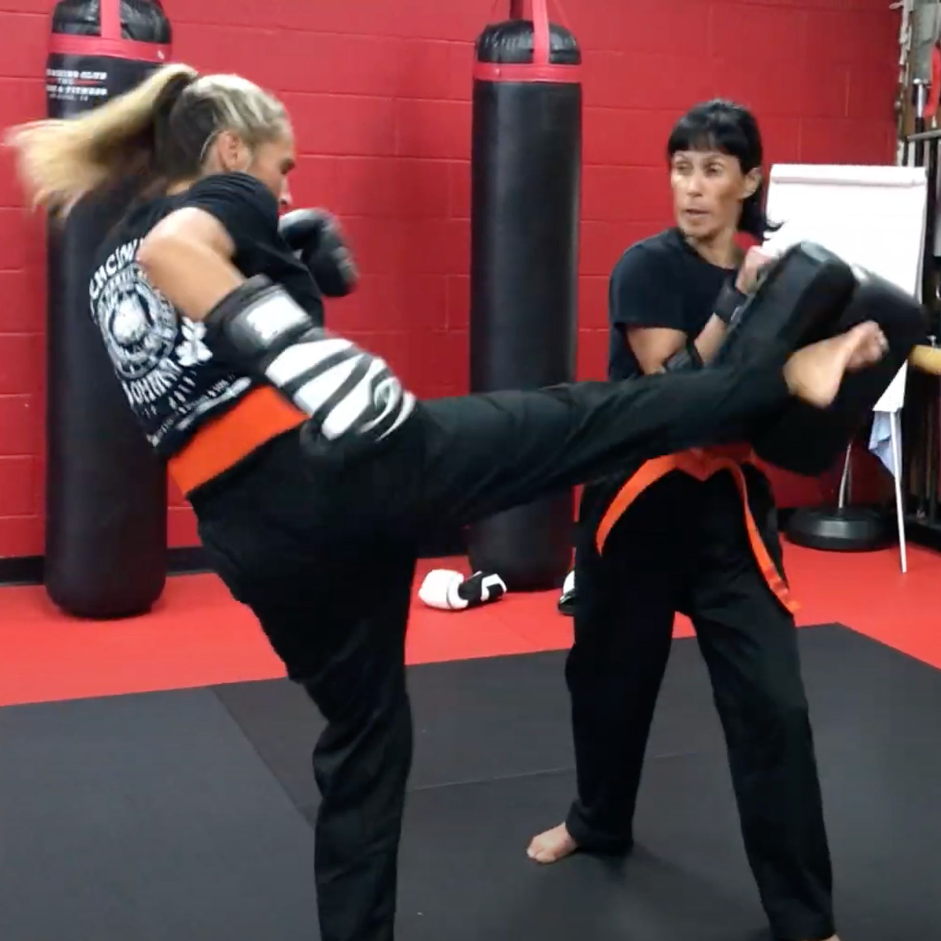 Two women are practicing martial arts in a gym