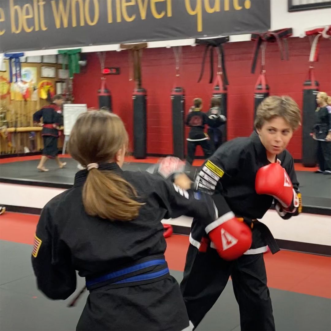 A man and a girl are boxing in a gym with a sign that says belt who never quit