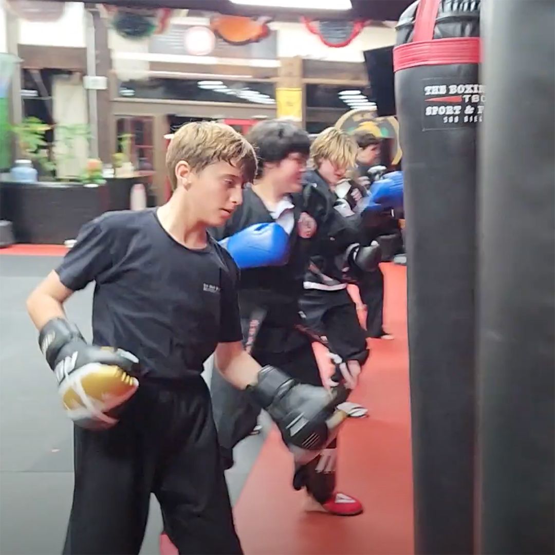 A group of young men are practicing martial arts in a gym