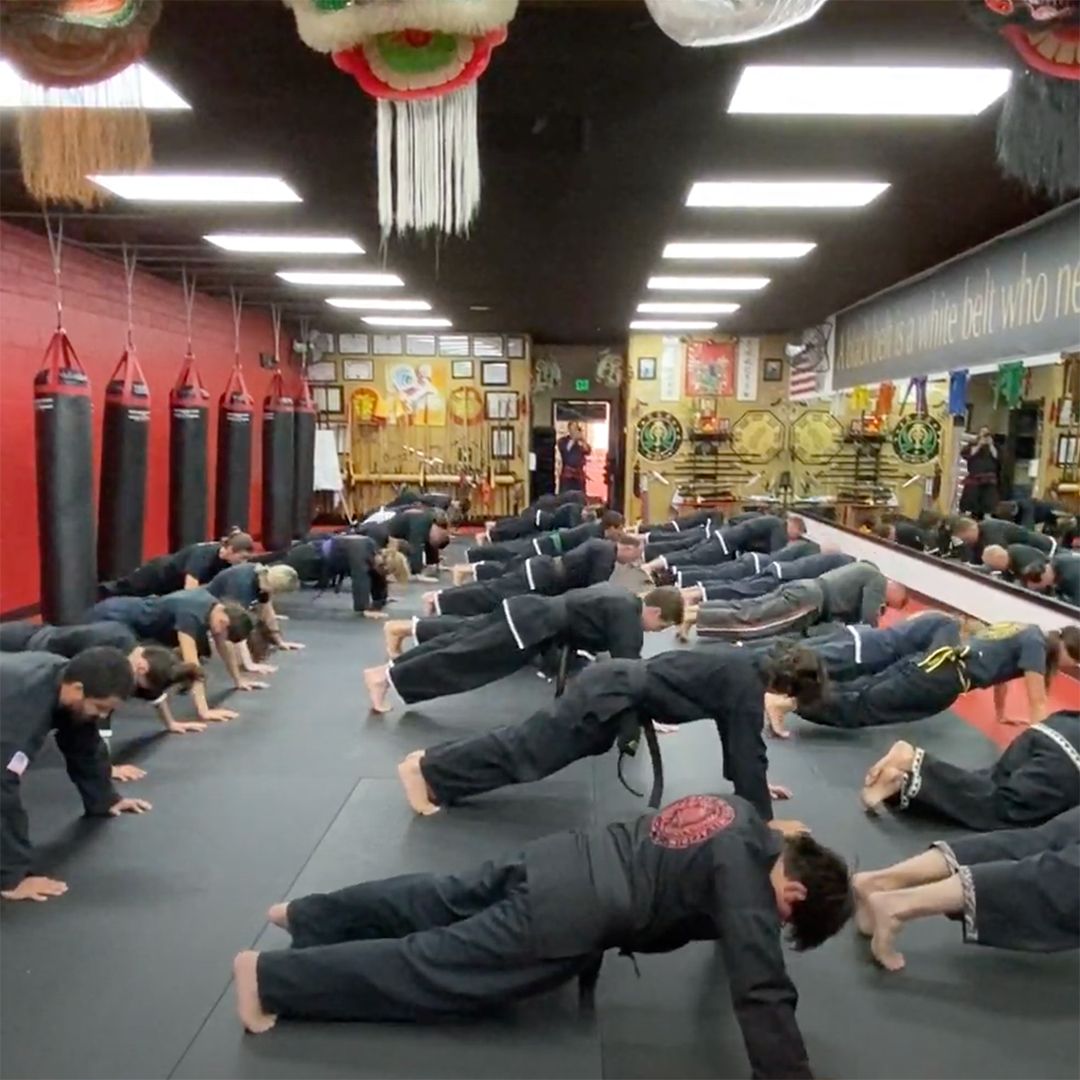 A group of people doing push ups in a gym