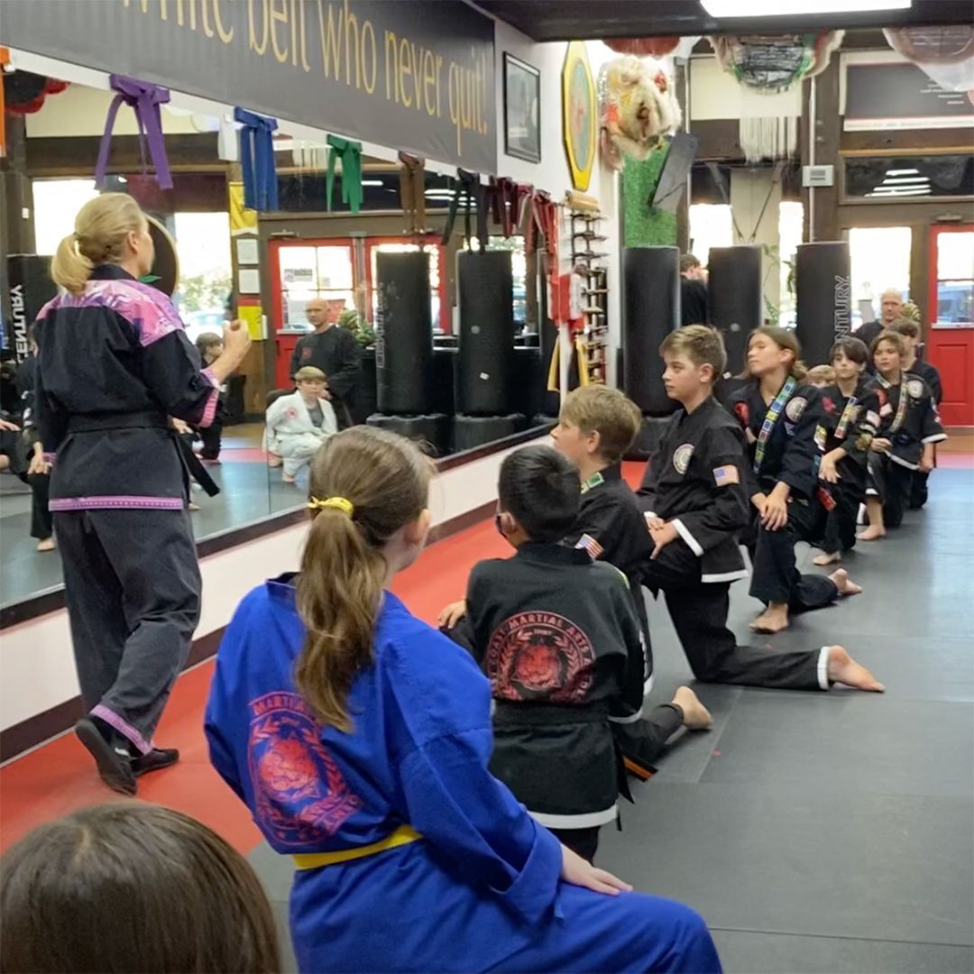 A group of kids are practicing martial arts in a gym