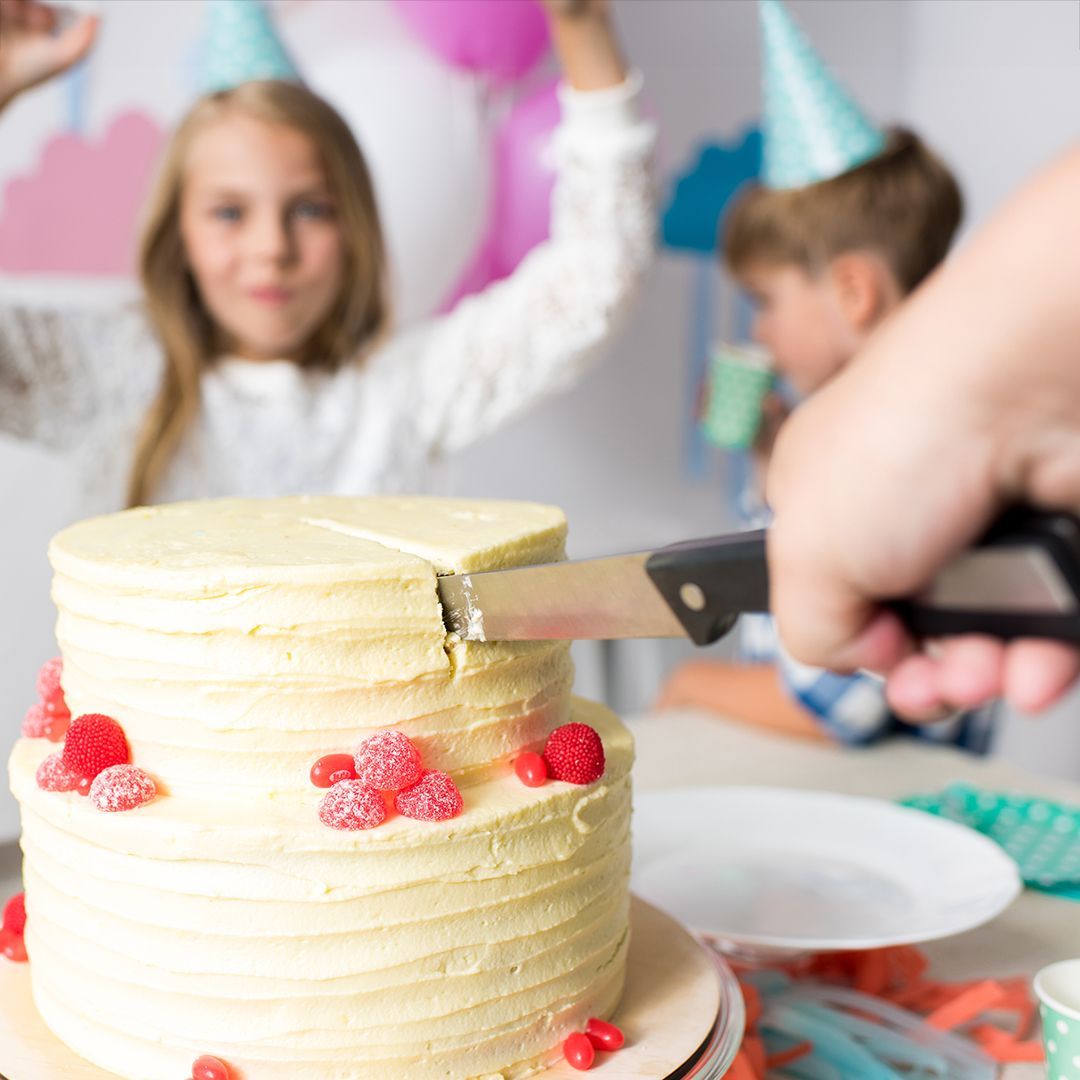 A person is cutting a cake with a pair of scissors