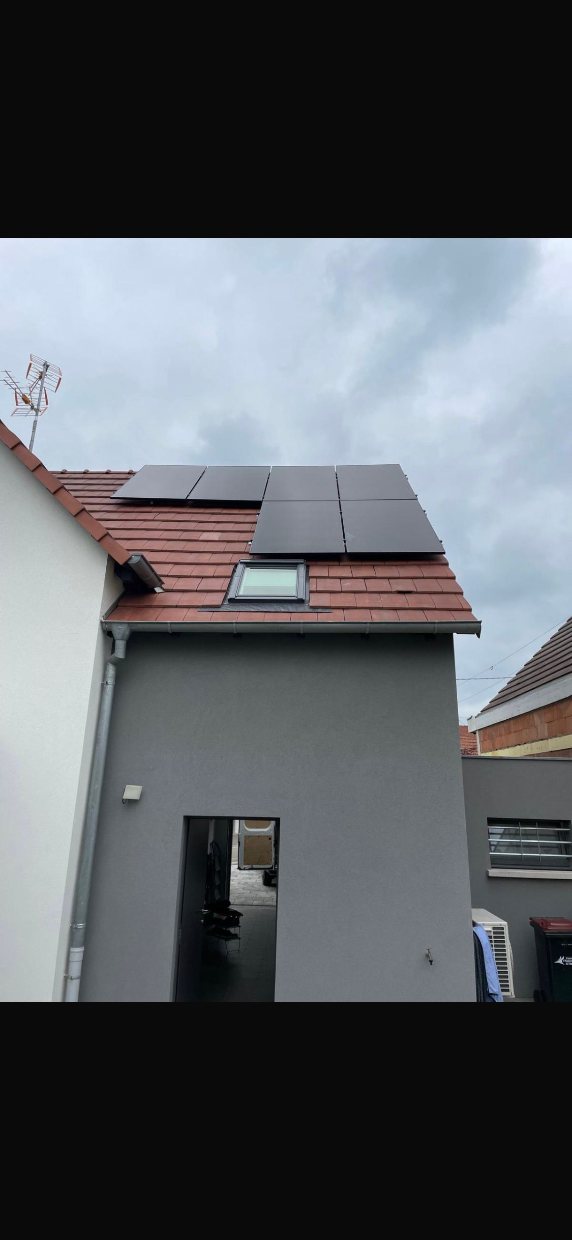 Une maison avec des panneaux solaires sur le toit et un puits de lumière.