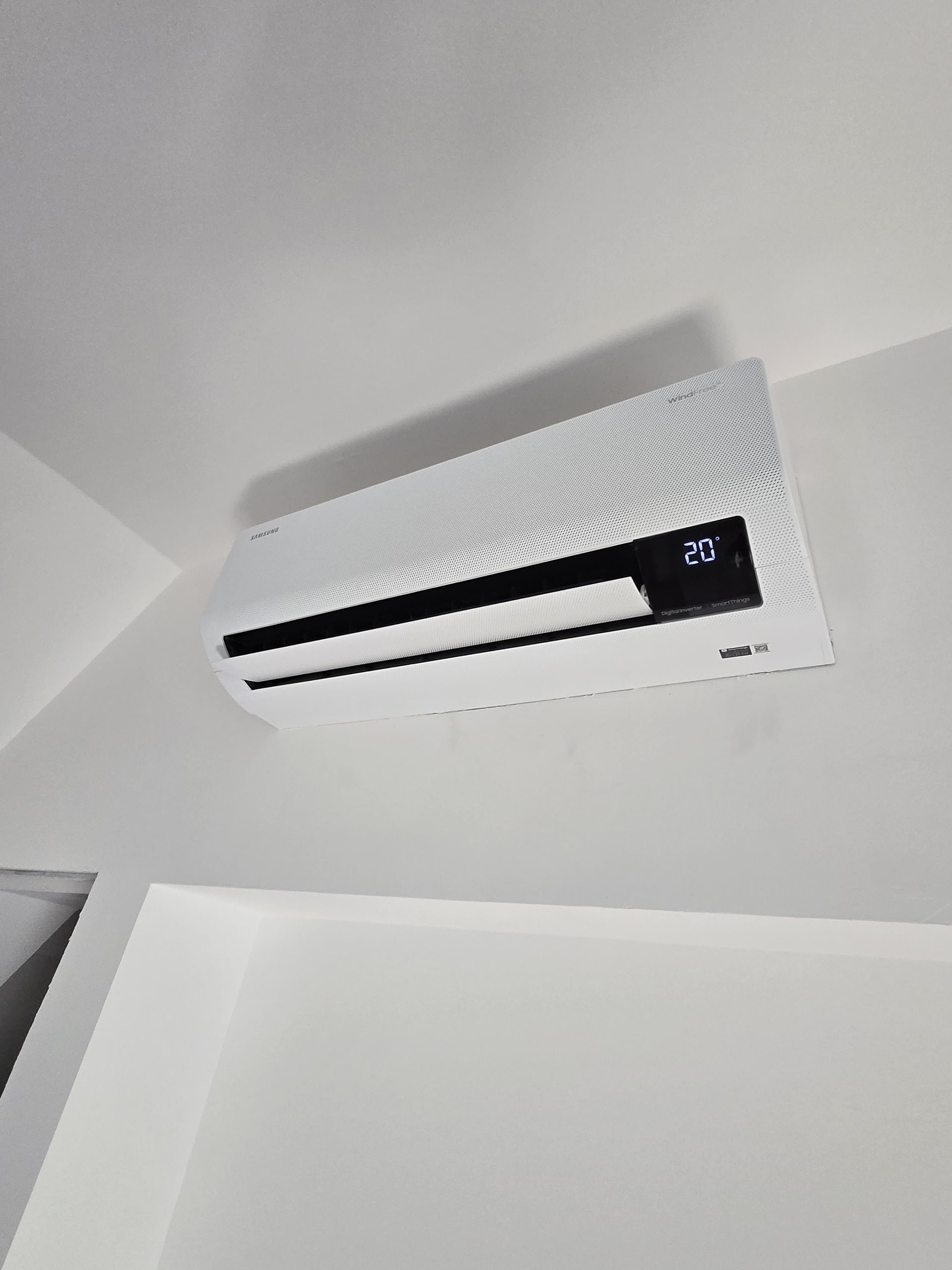 Un climatiseur blanc est suspendu au plafond d'une pièce.