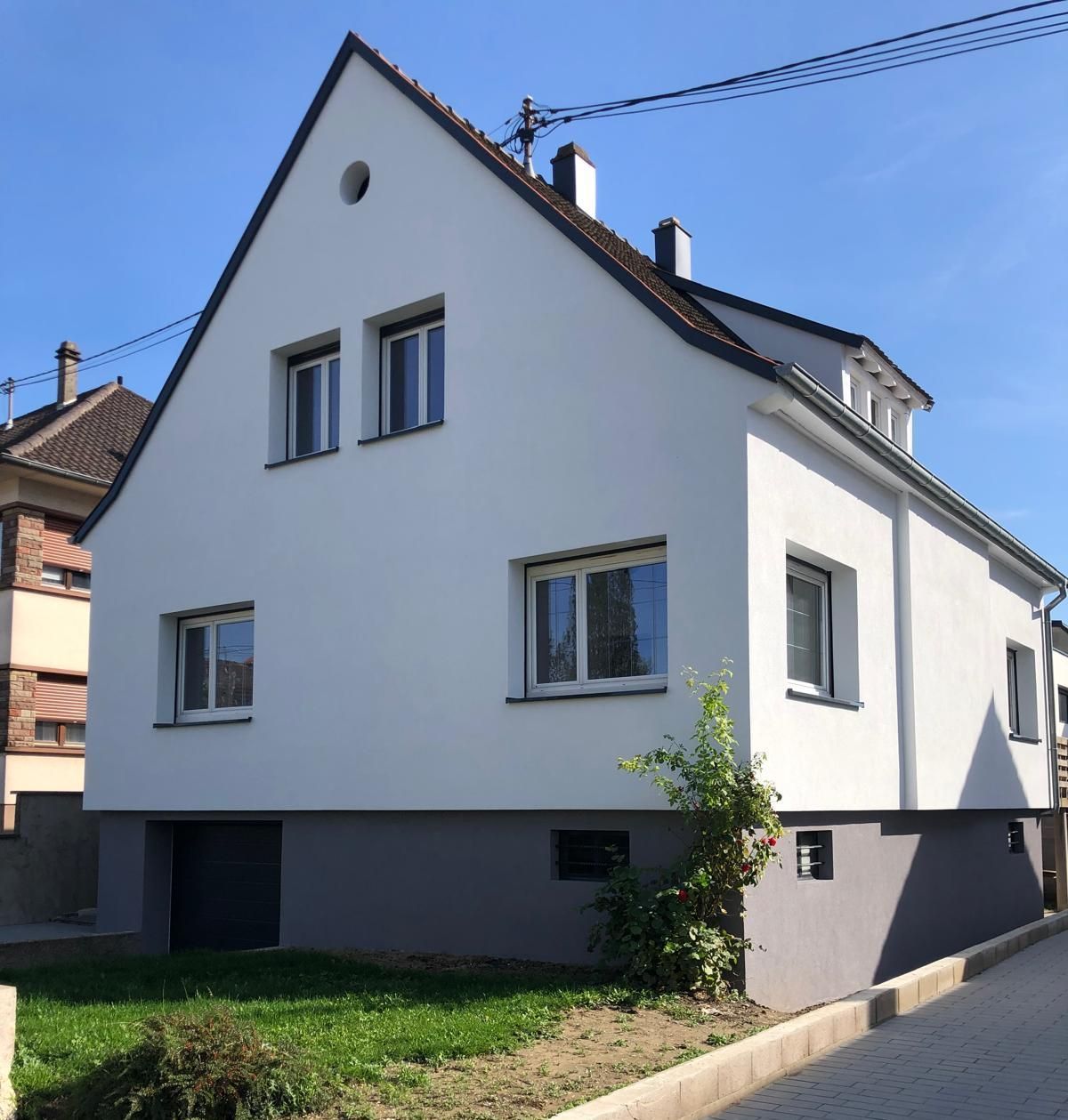 Une voiture blanche est garée devant une maison blanche
