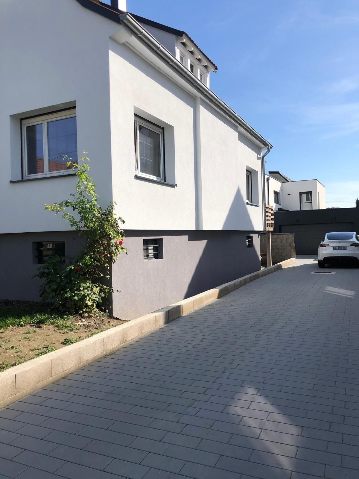 Une voiture blanche est garée devant une maison blanche