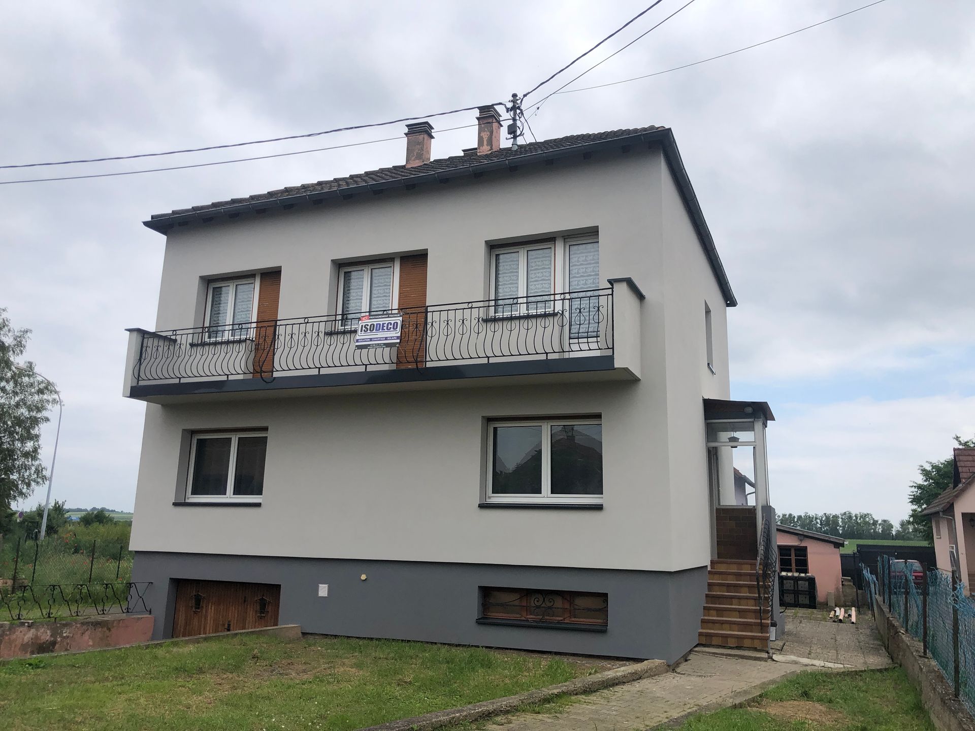 Une grande maison blanche avec un balcon et des escaliers