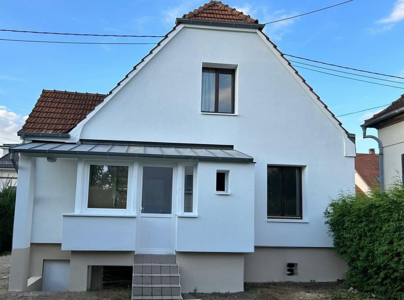 Une maison blanche avec des escaliers menant à la porte d'entrée
