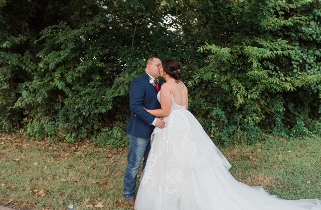A bride and groom are kissing in front of a forest.