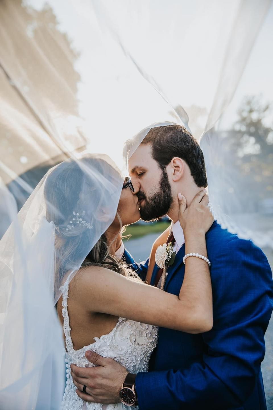 A bride and groom are kissing under a veil.